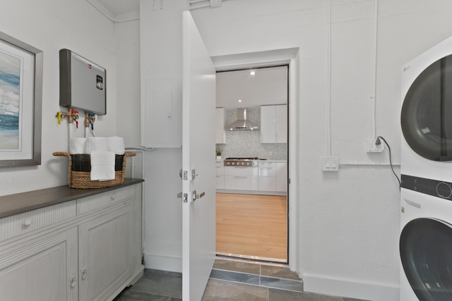 clothes washing area featuring stacked washer / dryer and tankless water heater