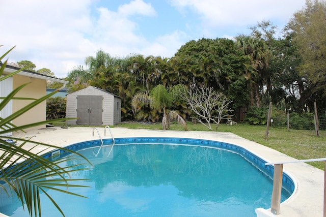 outdoor pool with a patio, a shed, a lawn, and an outdoor structure