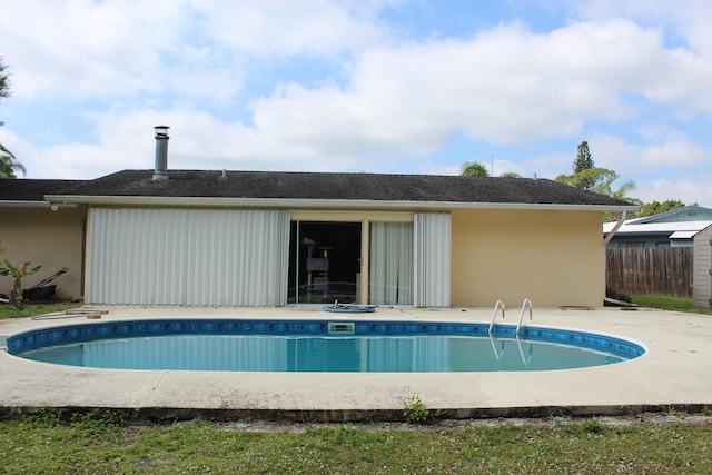 rear view of property with a patio, stucco siding, fence, and an outdoor pool