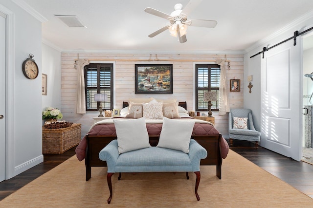 bedroom with wood walls, ceiling fan, a barn door, dark hardwood / wood-style floors, and ornamental molding