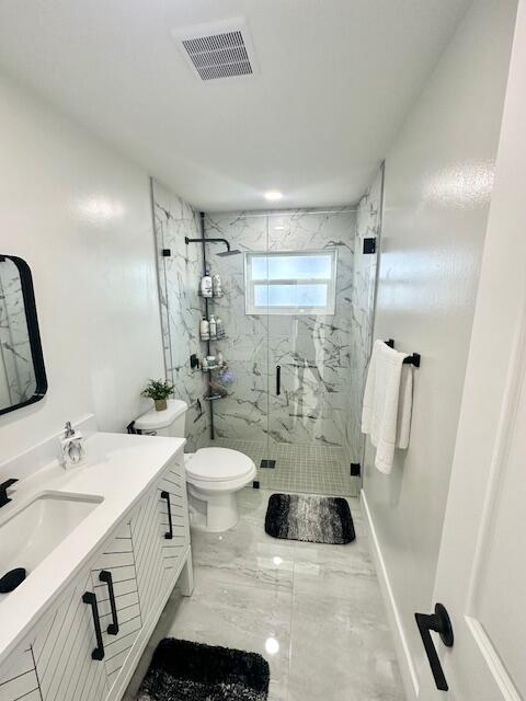 bathroom with vanity, toilet, and a shower with shower door