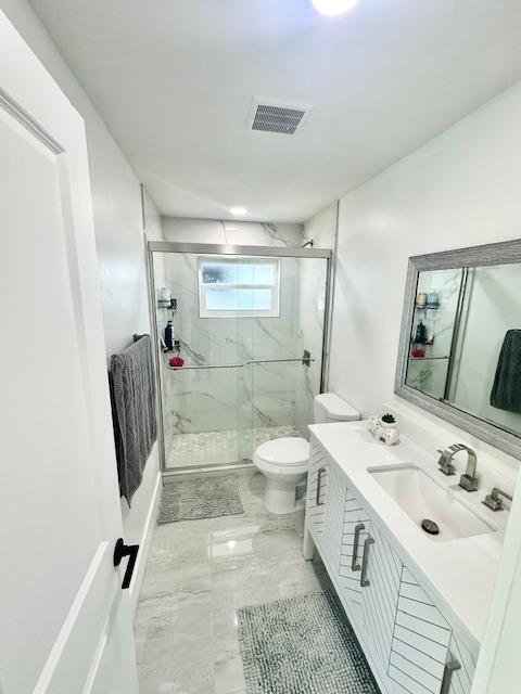 bathroom featuring vanity, toilet, and a shower with shower door