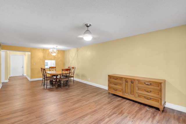 dining space with hardwood / wood-style floors, a textured ceiling, and an inviting chandelier