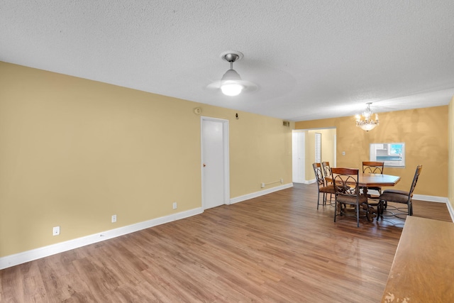 dining room featuring ceiling fan with notable chandelier, wood-type flooring, and a textured ceiling