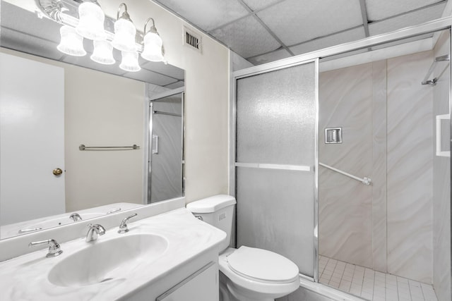 bathroom featuring a drop ceiling, toilet, an enclosed shower, and vanity