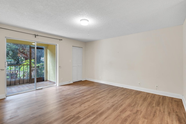 spare room featuring light hardwood / wood-style floors and a textured ceiling