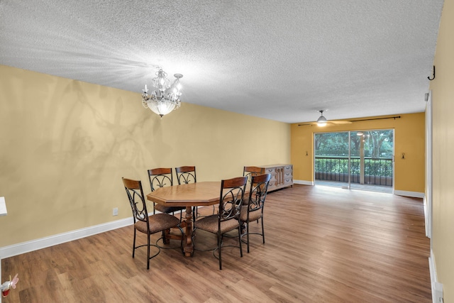 dining area with wood-type flooring, ceiling fan with notable chandelier, and a textured ceiling