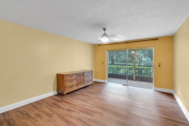 empty room with ceiling fan, a textured ceiling, and light wood-type flooring