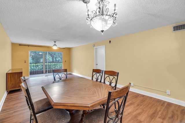 dining room featuring hardwood / wood-style flooring, ceiling fan with notable chandelier, and a textured ceiling