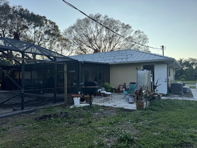 rear view of house with glass enclosure, a patio area, and central air condition unit