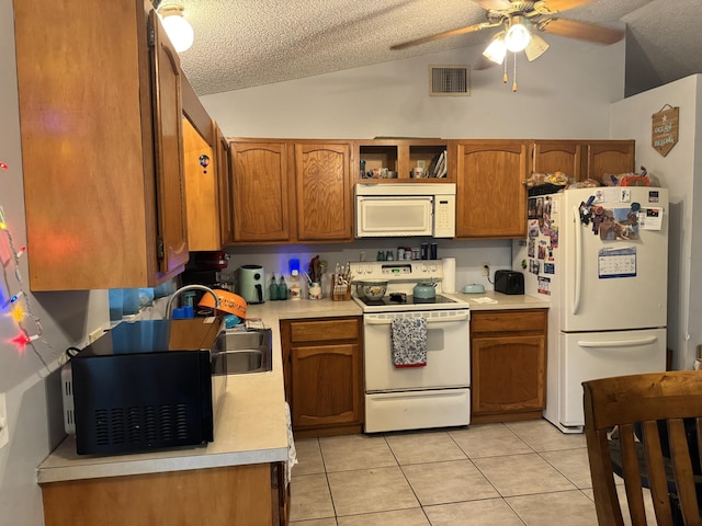 kitchen with ceiling fan, vaulted ceiling, a textured ceiling, white appliances, and light tile patterned floors