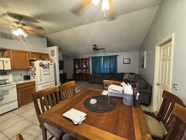 dining area featuring a textured ceiling, vaulted ceiling, and light tile patterned flooring