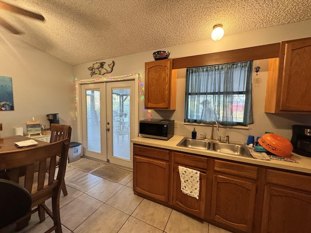 kitchen featuring light tile patterned flooring, french doors, a textured ceiling, and sink