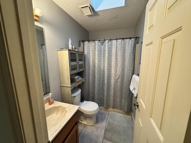 bathroom featuring vanity, tile patterned floors, a skylight, toilet, and a textured ceiling