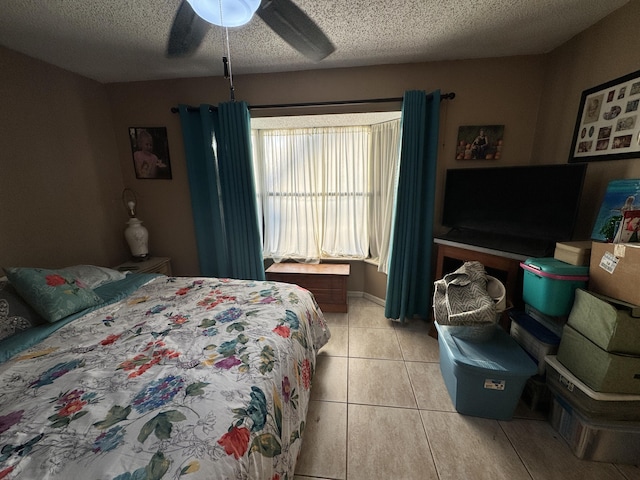 bedroom featuring ceiling fan, light tile patterned floors, and a textured ceiling