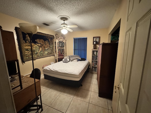 tiled bedroom with ceiling fan and a textured ceiling