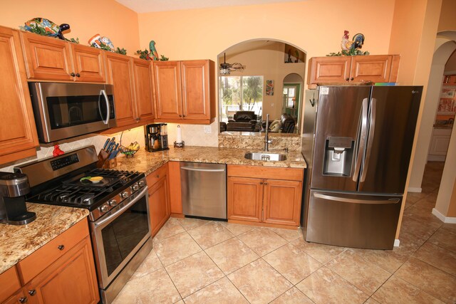 kitchen featuring sink, ceiling fan, light stone countertops, and appliances with stainless steel finishes