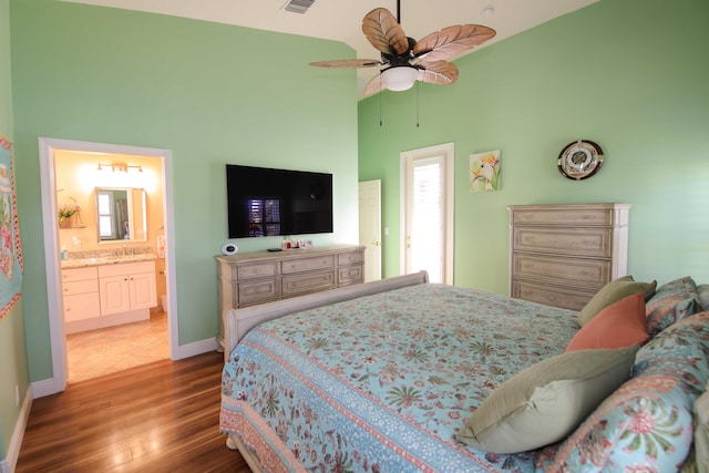 bedroom with hardwood / wood-style floors, a high ceiling, ensuite bath, and ceiling fan