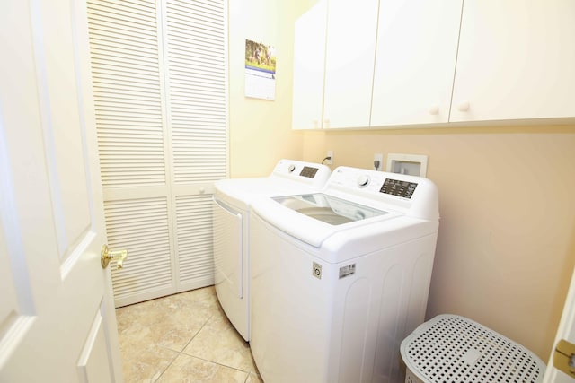 laundry area featuring washer and clothes dryer, light tile patterned floors, and cabinets