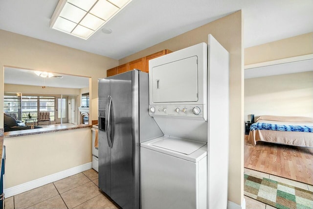 laundry area featuring light tile patterned flooring and stacked washer / dryer