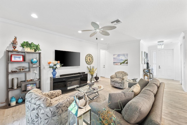 living room featuring a textured ceiling, ceiling fan, ornamental molding, and light hardwood / wood-style flooring