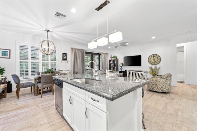 kitchen with a kitchen island with sink, dark stone counters, hanging light fixtures, white cabinets, and sink