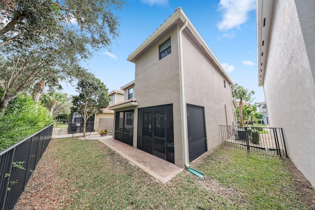 back of property with a sunroom and a lawn