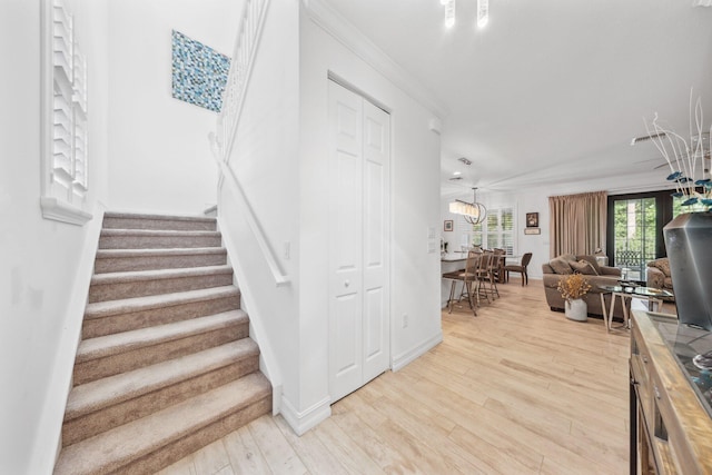 staircase featuring wood-type flooring and crown molding