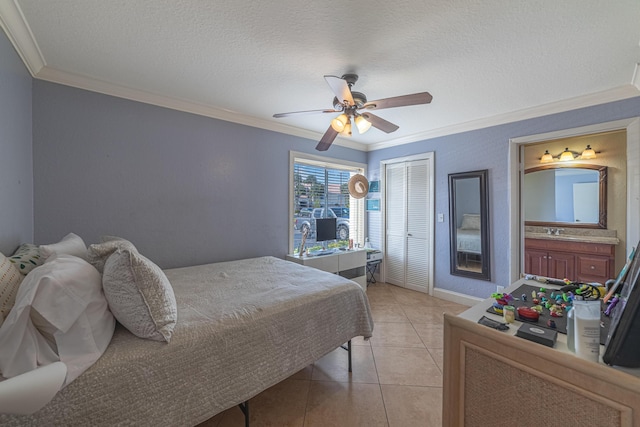 tiled bedroom featuring ensuite bath, ceiling fan, crown molding, a textured ceiling, and a closet