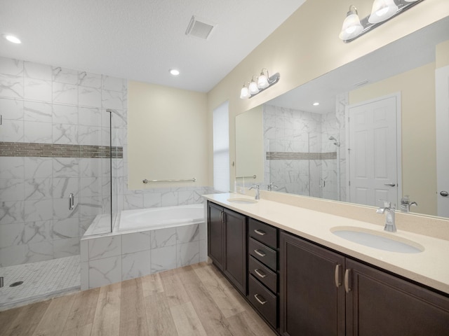 bathroom with vanity, independent shower and bath, hardwood / wood-style floors, and a textured ceiling