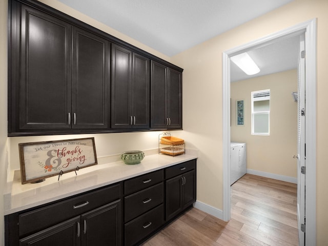 washroom with washing machine and clothes dryer and light wood-type flooring