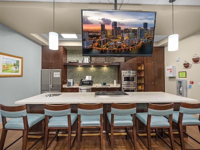 kitchen with decorative light fixtures, a kitchen bar, decorative backsplash, stainless steel appliances, and dark brown cabinets