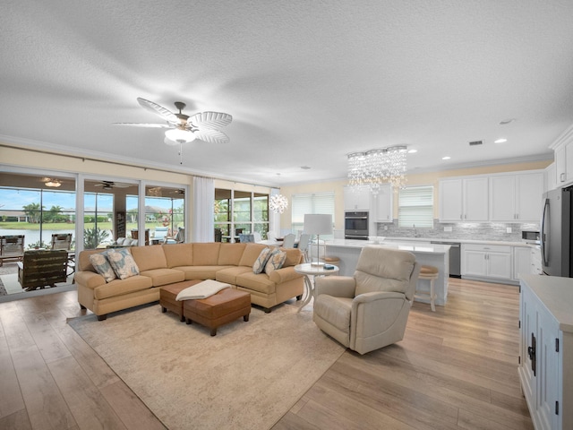 living room with crown molding, sink, ceiling fan, and light hardwood / wood-style floors