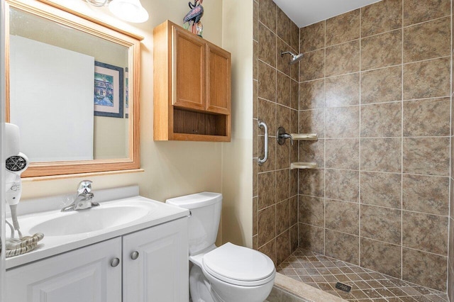 bathroom with tiled shower, vanity, and toilet