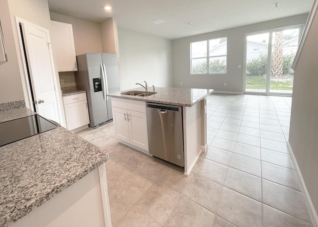 kitchen with stainless steel appliances, a kitchen island with sink, white cabinetry, and sink