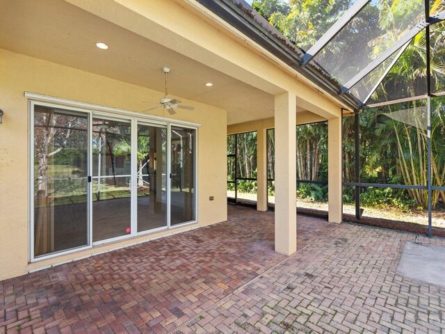 view of patio with ceiling fan and glass enclosure