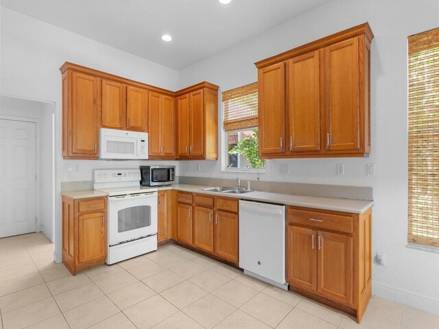 kitchen featuring sink, light tile patterned flooring, and white appliances