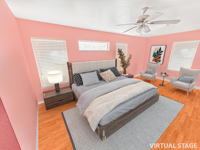 bedroom with hardwood / wood-style floors, ceiling fan, and a textured ceiling