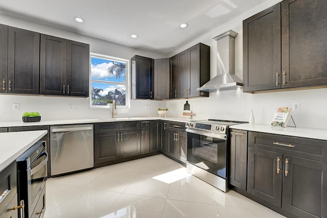 kitchen featuring appliances with stainless steel finishes, sink, light tile patterned floors, dark brown cabinetry, and wall chimney exhaust hood