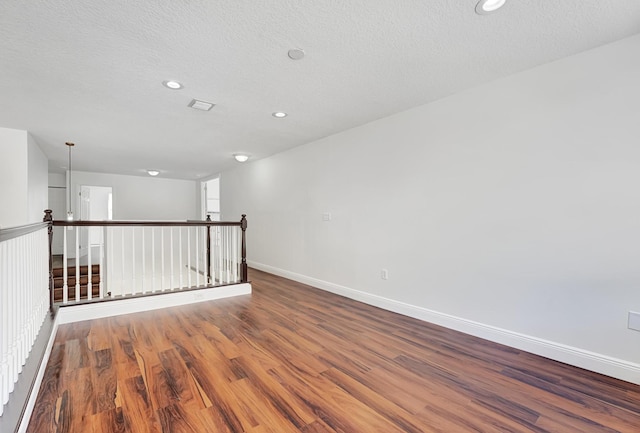 empty room featuring wood-type flooring and a textured ceiling