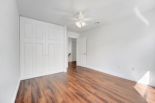 unfurnished bedroom featuring ceiling fan, dark hardwood / wood-style floors, a closet, and a textured ceiling