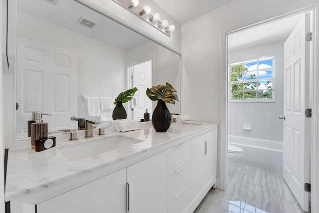 bathroom featuring vanity, a tub to relax in, and toilet