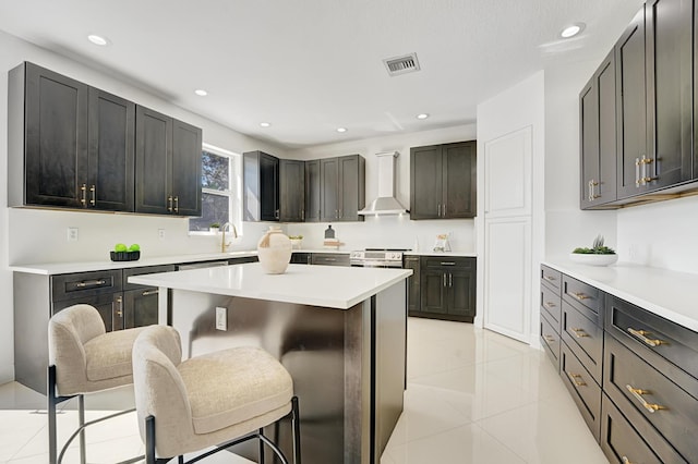 kitchen featuring sink, a breakfast bar, wall chimney exhaust hood, and a center island