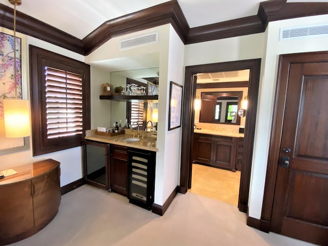 bar featuring sink, beverage cooler, light carpet, dark brown cabinets, and ornamental molding