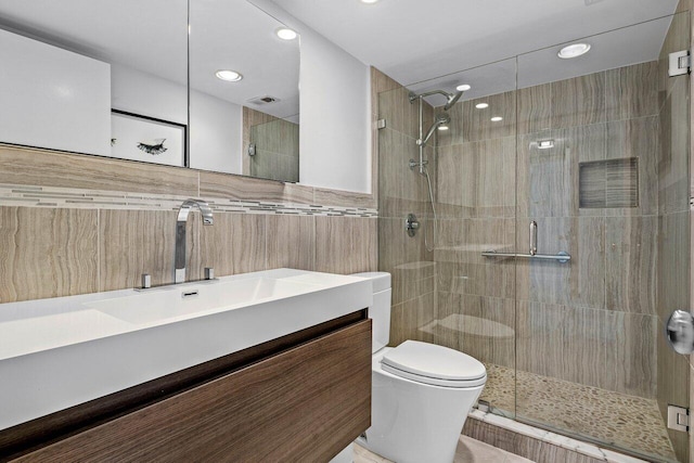 bathroom with toilet, tile walls, a shower with door, and vanity