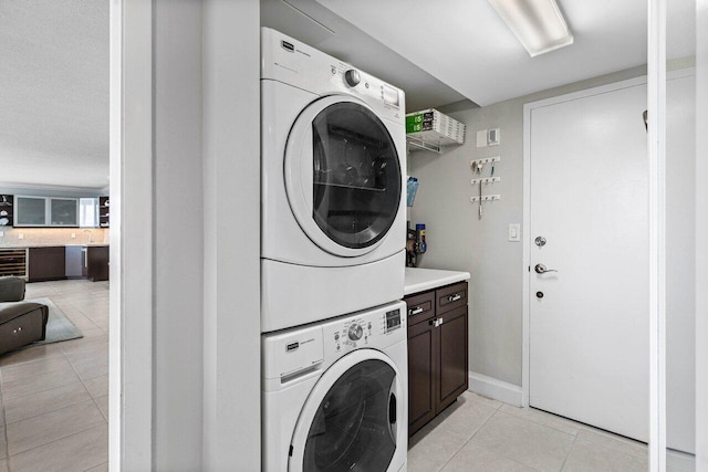 washroom featuring wine cooler, stacked washing maching and dryer, light tile patterned floors, and cabinets