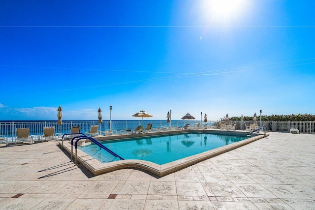 view of pool with a patio area and a water view