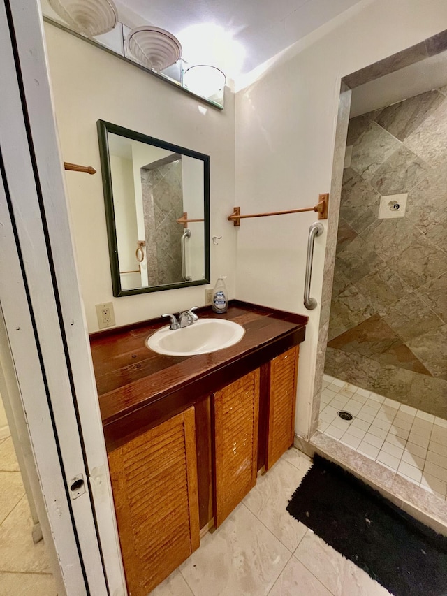 bathroom featuring tile patterned flooring, vanity, and tiled shower