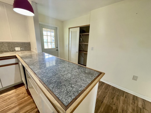 kitchen featuring kitchen peninsula, hardwood / wood-style floors, and white cabinetry