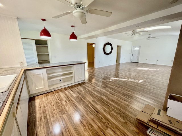 kitchen with vaulted ceiling, ceiling fan, hardwood / wood-style flooring, white cabinetry, and hanging light fixtures